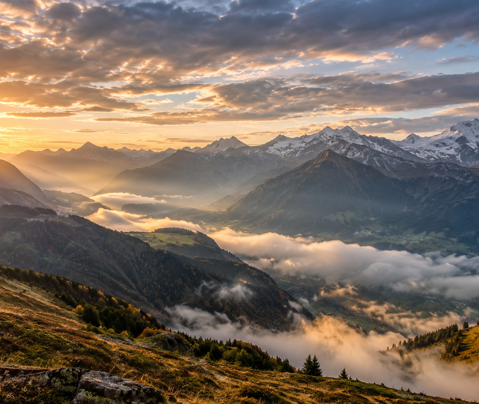 European mountain valley under dramatic sunrise light with fog, clear ridges and early autumn conditions
