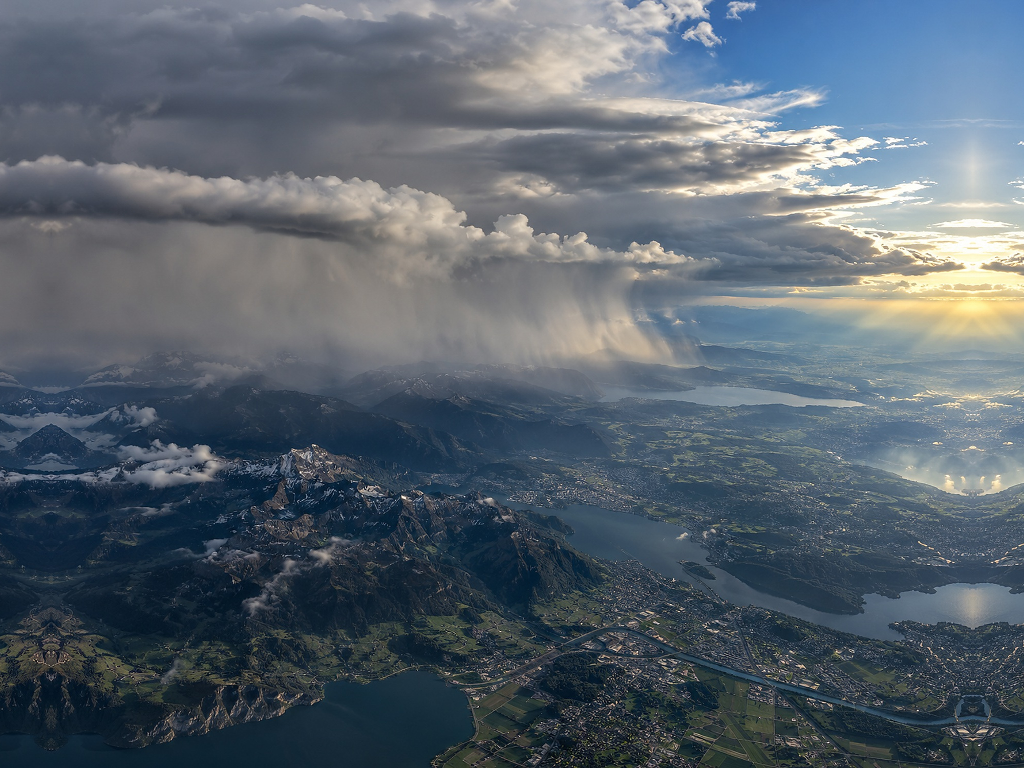 Dramatic European mountain weather with cloud bands, showers, snow-capped peaks and bright breaks