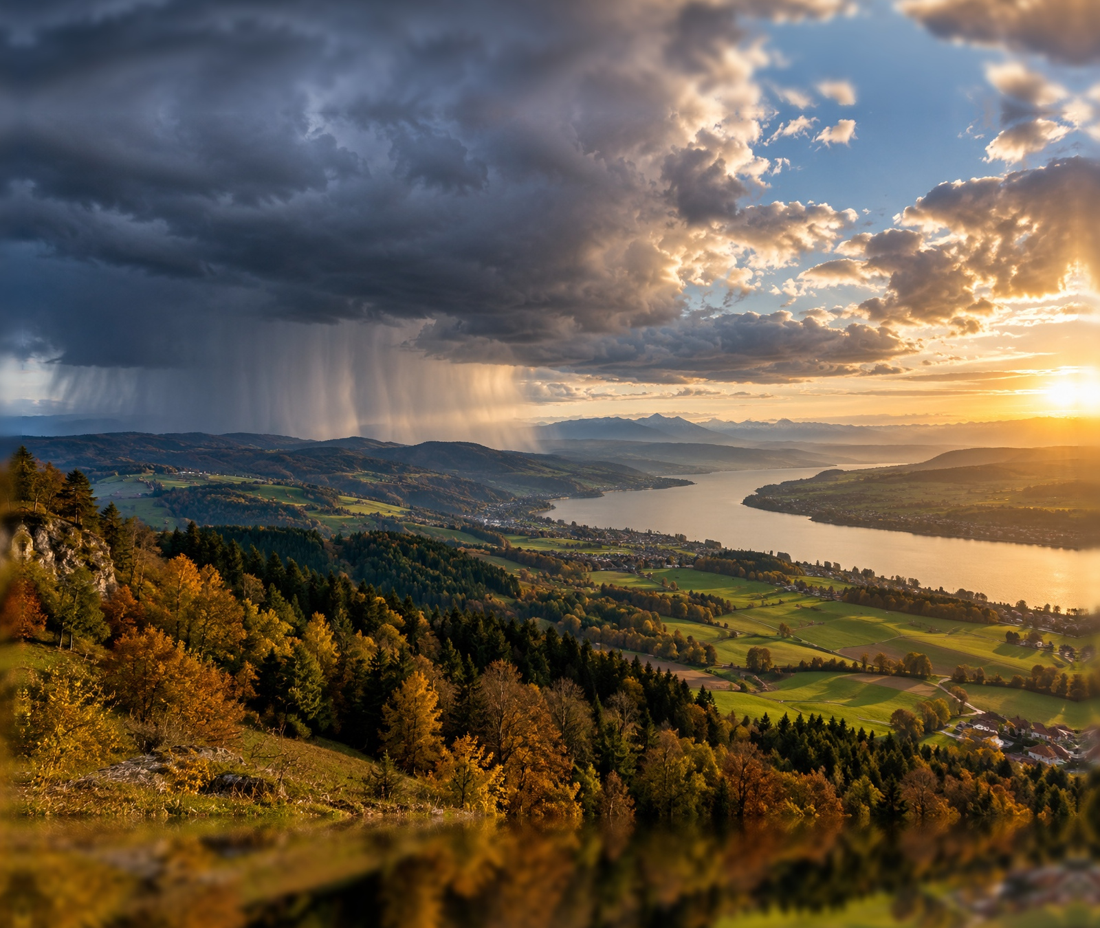 European autumn landscape with rain clouds in the west and evening sunshine in the east
