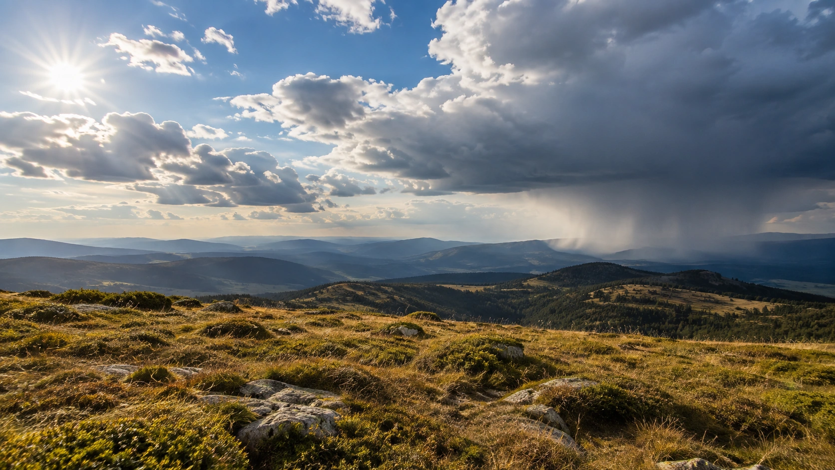 Open highland landscape showing bright sunshine on one side and a distant rain band on the other.