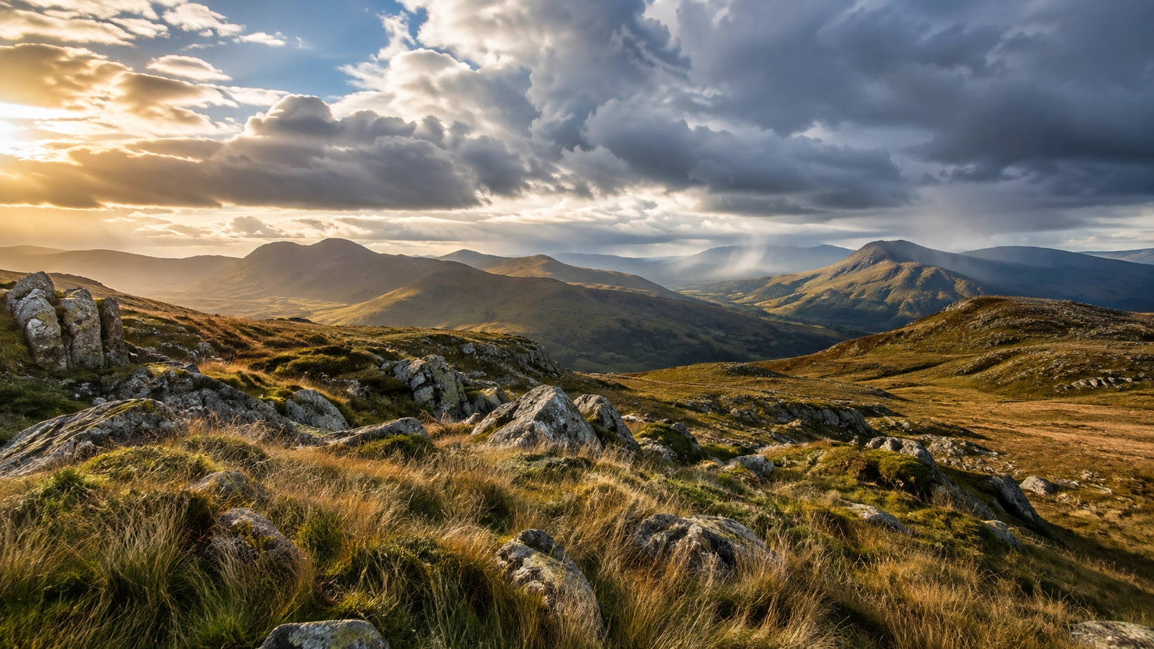 Open mountain wilderness with sunlit ridges, darker storm clouds and distant rain over rolling terrain.