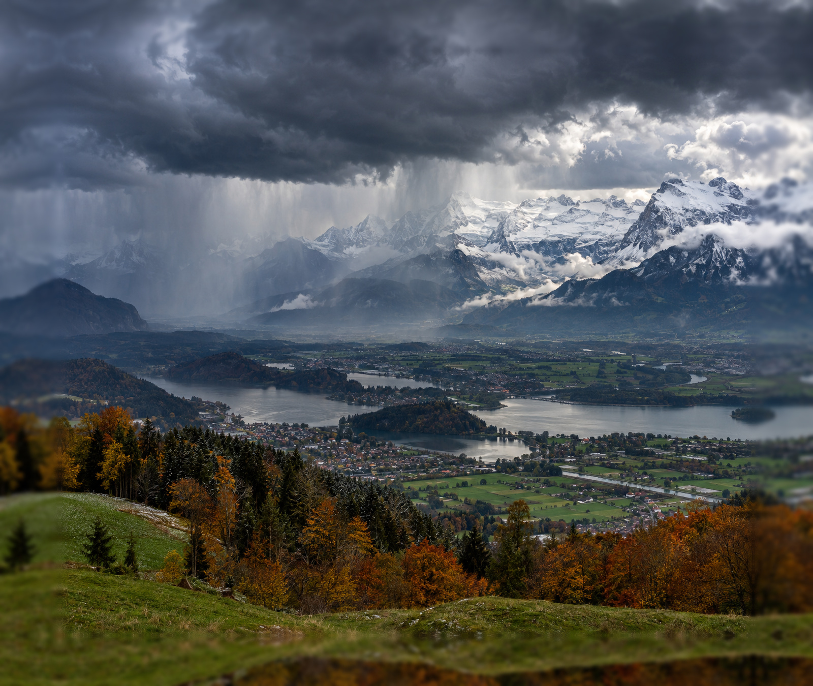 Stormy autumn weather across an Alpine landscape with rain in the valleys and fresh snow on the high mountains.